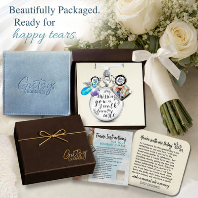 A beautifully packaged bouquet arrangement gift set from Gutsy Goodness, featuring a blue fabric pouch, a clear bag filled with white flowers and gold glitter, a brown gift box tied with gold ribbon, an open box with a silver keepsake card, printed instructions, and a white card, styled with white roses on a white background.