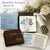 A beautifully packaged bouquet arrangement gift set from Gutsy Goodness, featuring a blue fabric pouch, a clear bag filled with white flowers and gold glitter, a brown gift box tied with gold ribbon, an open box with a silver keepsake card, printed instructions, and a white card, styled with white roses on a white background.