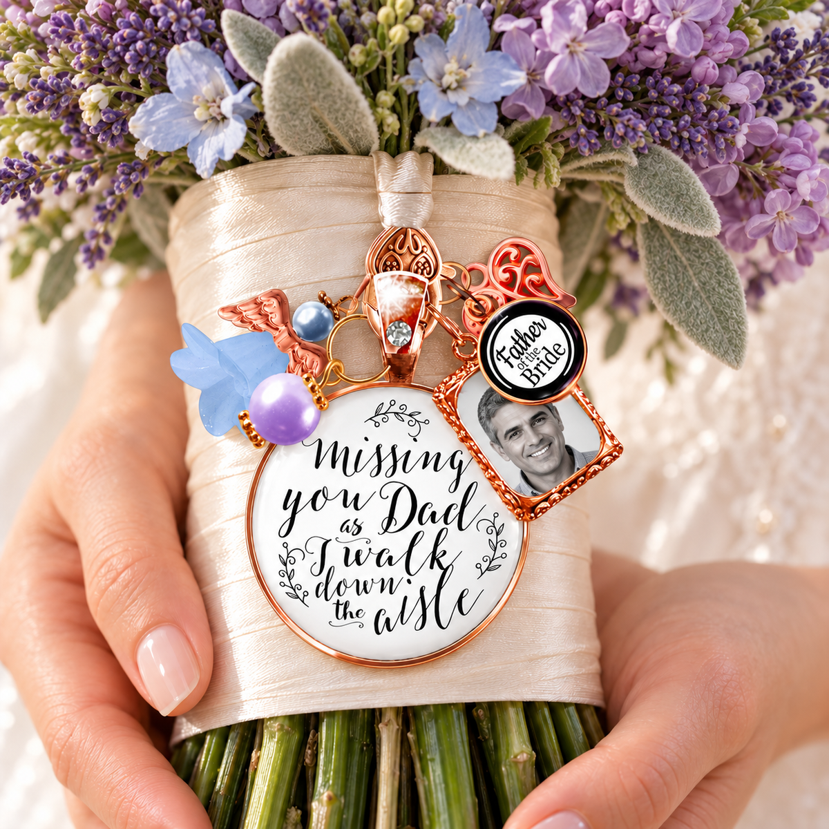 Personalized rose gold bridal bouquet memorial charm pinned to a cream ribbon-wrapped lavender floral bouquet, featuring a custom father photo frame, "Father of the Bride" charm, angel wing, something blue flower, and scripted quote: "Missing you Dad as I walk down the aisle."